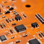entegre transistör kondansatör direnç gibi malzemelerin bir araya geldiği turuncu tonlarda uzak açıdan alınmış elektronik ürün resmi